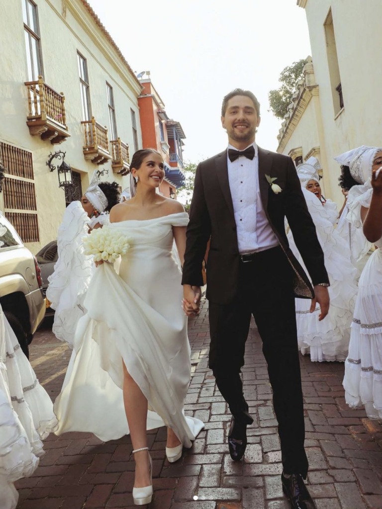 Lauren Giraldo and her husband walking down the street in a white dress, performing their wedding day task.