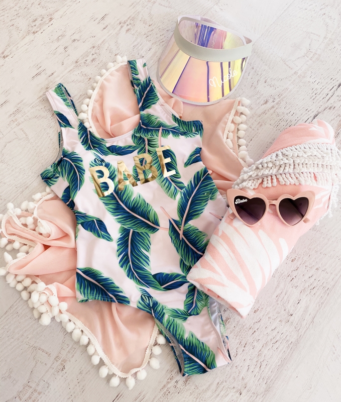 Pink tropical swimsuit with vibrant green palm leaves pattern, perfect for a stylish and fun beach day.