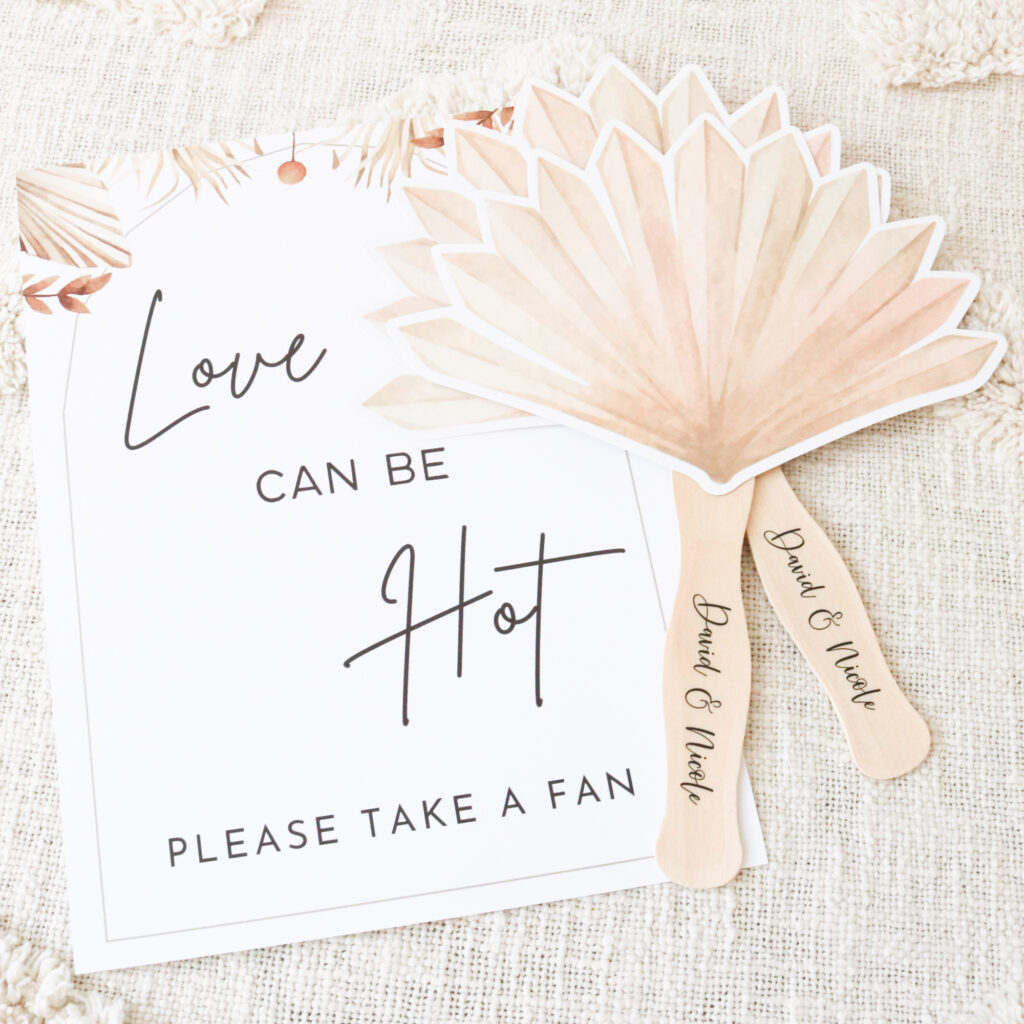 Beige Palm Leaf die cut paddle fans with a custom name personalization on the handle of the newly wed couple makes for a perfect wedding favor on a hot summer day.